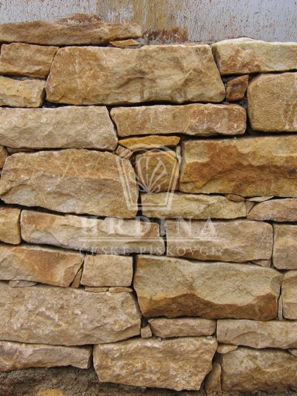 Detail pískovcové zdi s přirozenou strukturou a barevnými odstíny kamene